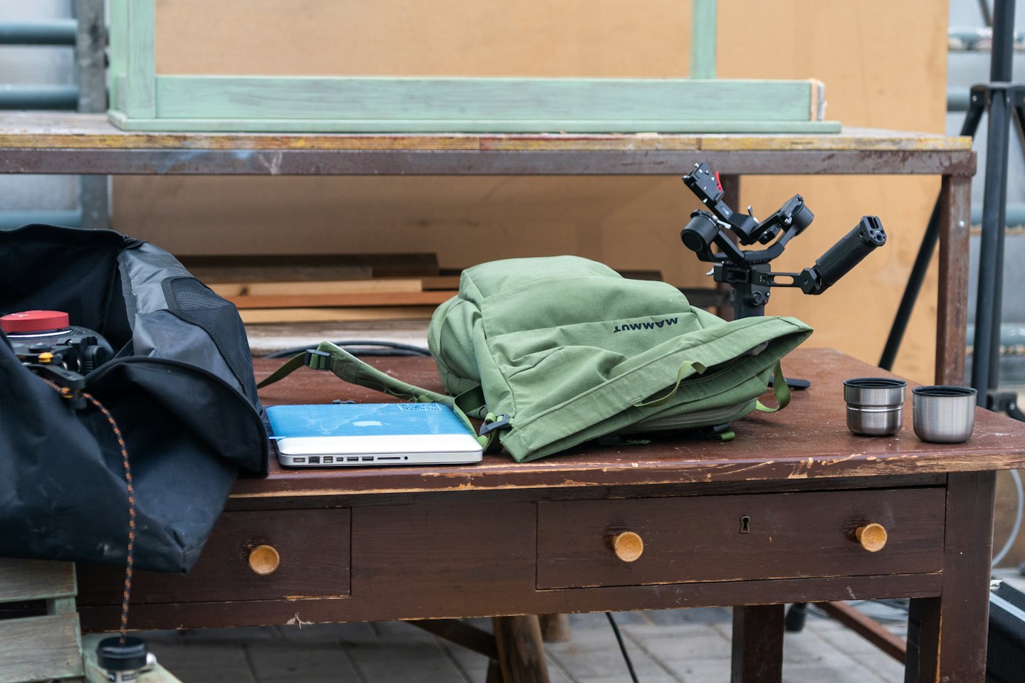 Drewniany stół ze sprzętem fotograficznym i plecakami.